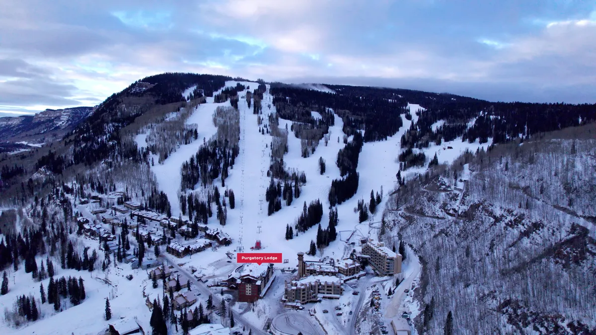 This exterior image captures the snow-covered slopes right beside Purgatory Lodge, with ski lifts ascending the mountains and pine trees framing the scene. The lodge itself is visible, emphasizing its direct proximity to the slopes and lifts. The snowy landscape is tranquil yet inviting, perfect for skiers and snowboarders eager to hit the mountain immediately.